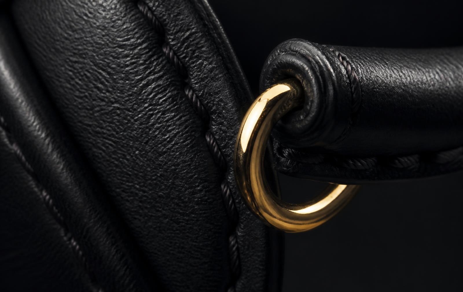 Macro detail of leather grain, stitching and a gold-tone ring